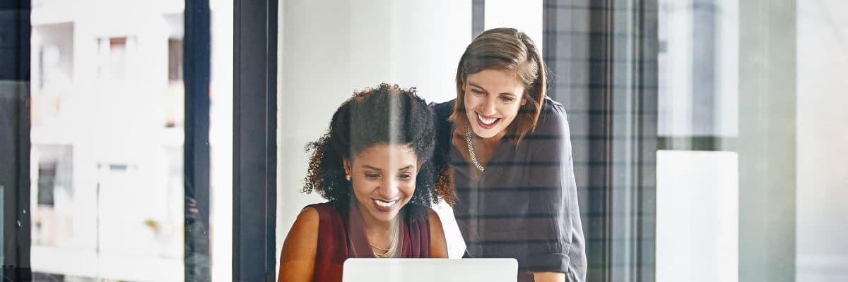 Two Business Women Looking at a Laptop Screen Smiling