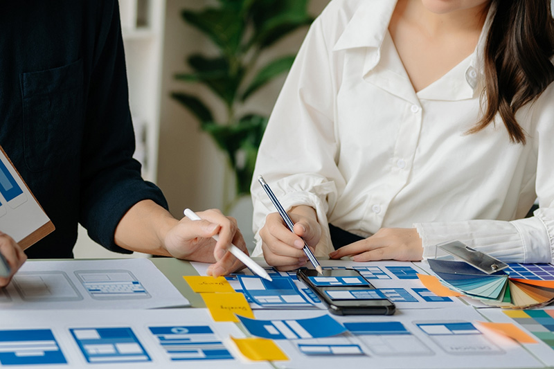 Two people are collaborating on a user interface design project