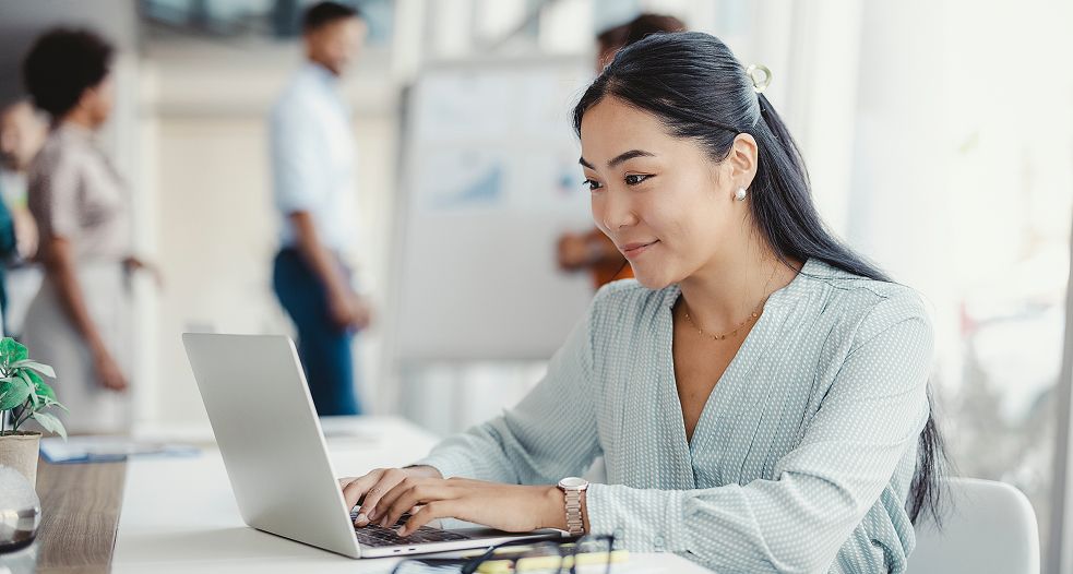 Image shows a professional woman working on her laptop.