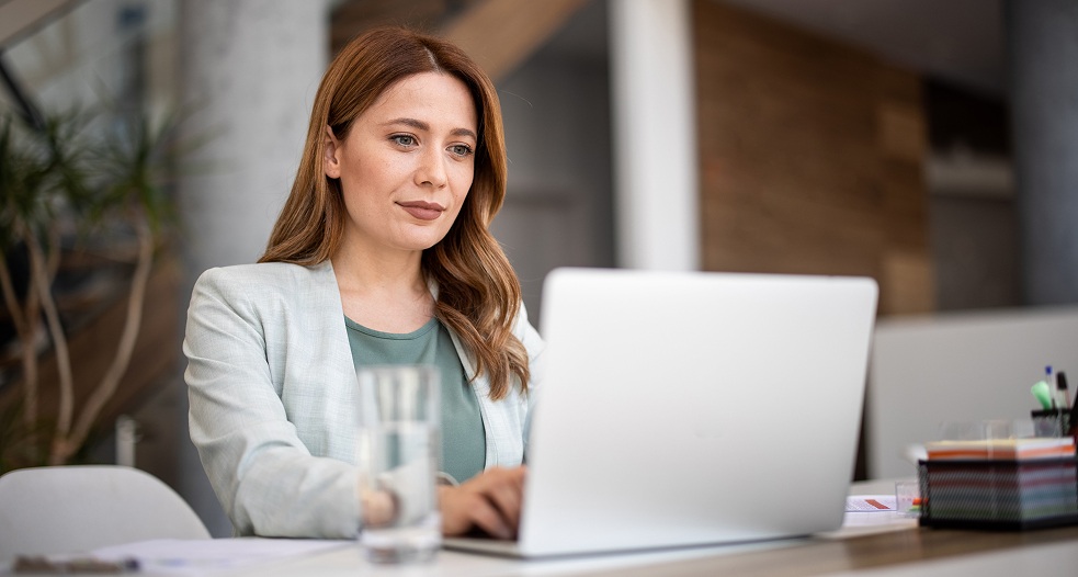 Image shows a professional woman working on her laptop.