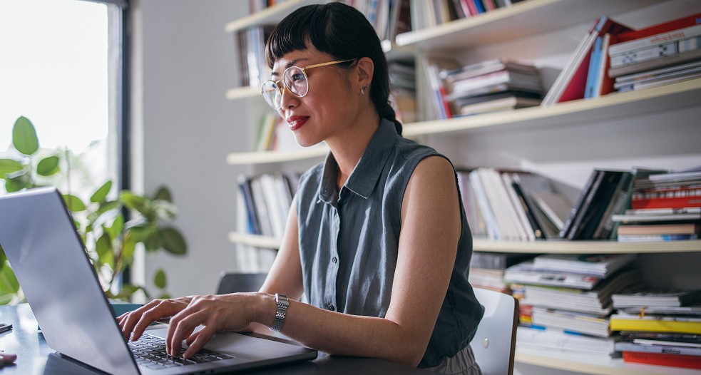 Image shows a professional woman working on her laptop.