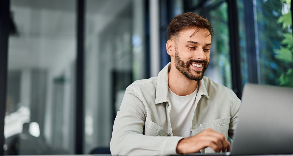 A man smiling while on his laptop