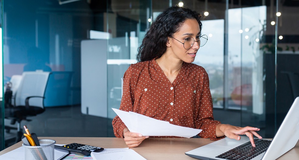 Image shows a professional woman working on her laptop.